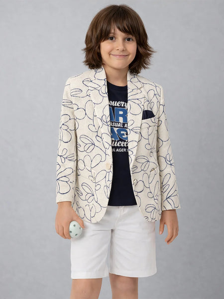 Child wearing a patterned blazer and white shorts on a plain background