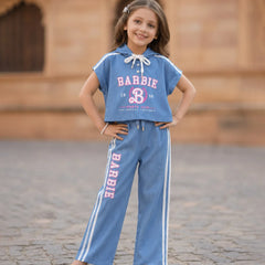 Young girl wearing a Barbie-themed outfit with a blue shirt and pants on a stone pavement.