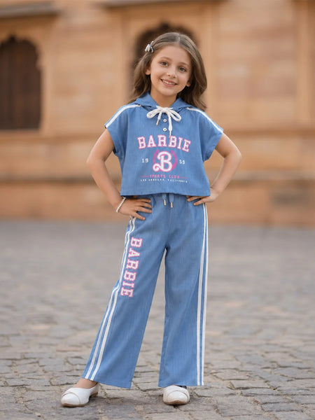 Young girl wearing a Barbie-themed outfit with a blue shirt and pants on a stone pavement.