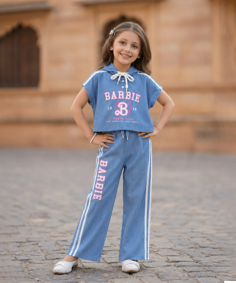 Young girl wearing a Barbie-themed outfit with a blue shirt and pants on a stone pavement.