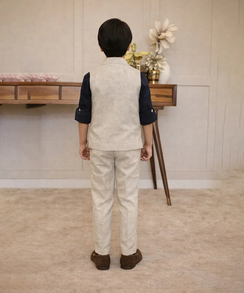 Child wearing a formal outfit standing in a room with a wooden desk and decorative items.