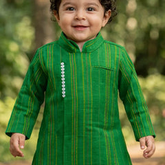 Child wearing a green traditional outfit with a blurred natural background