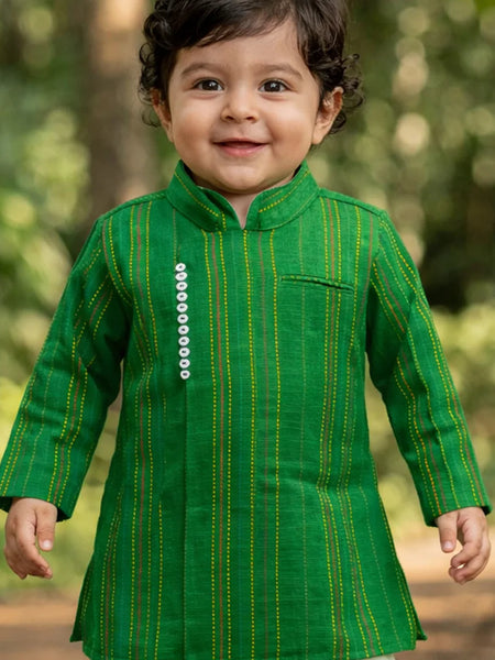 Child wearing a green traditional outfit with a blurred natural background