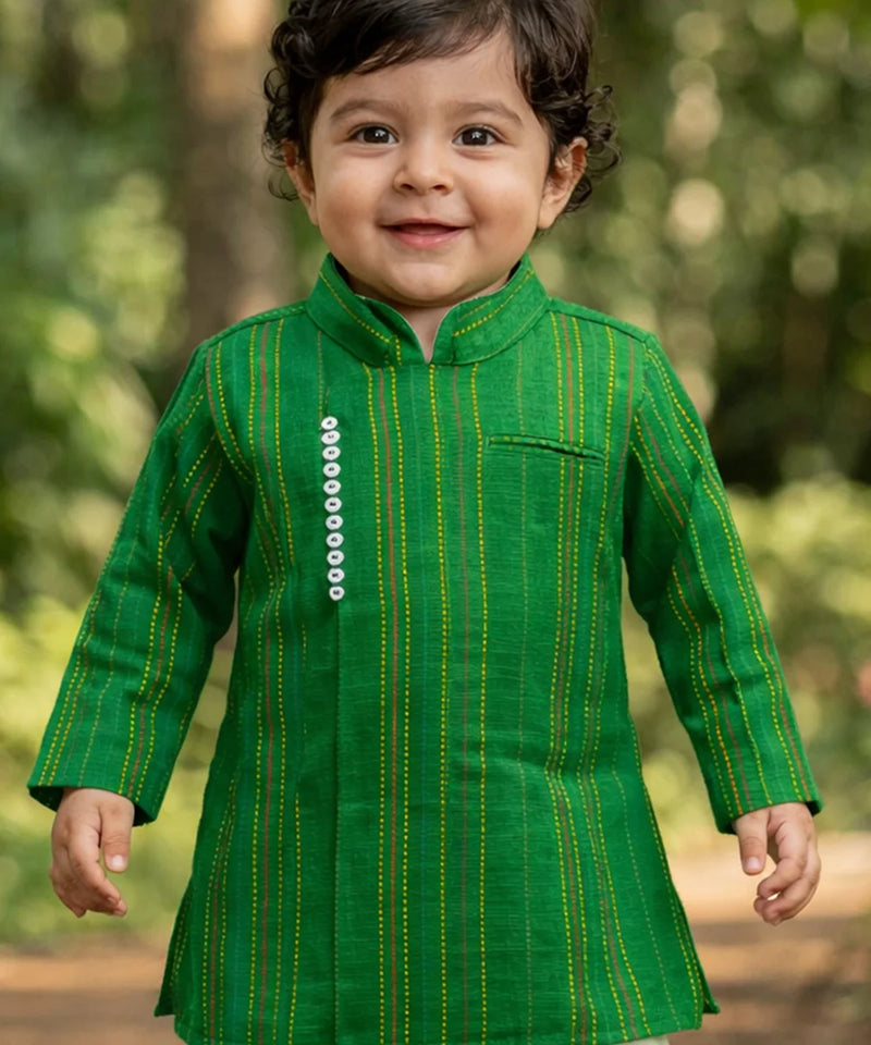 Child wearing a green traditional outfit with a blurred natural background