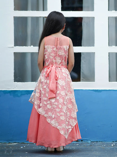 Woman wearing a pink lace dress with a blue wall and white window frame in the background