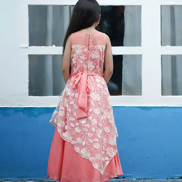Woman wearing a pink lace dress with a blue wall and white window frame in the background