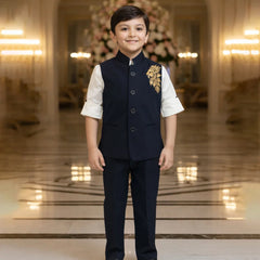 Young boy in formal attire standing in an elegant interior setting with chandeliers.
