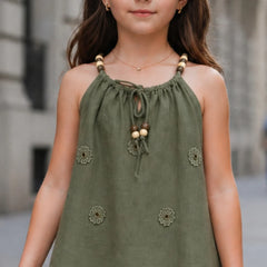 Young girl wearing a green top with floral embellishments in an urban setting