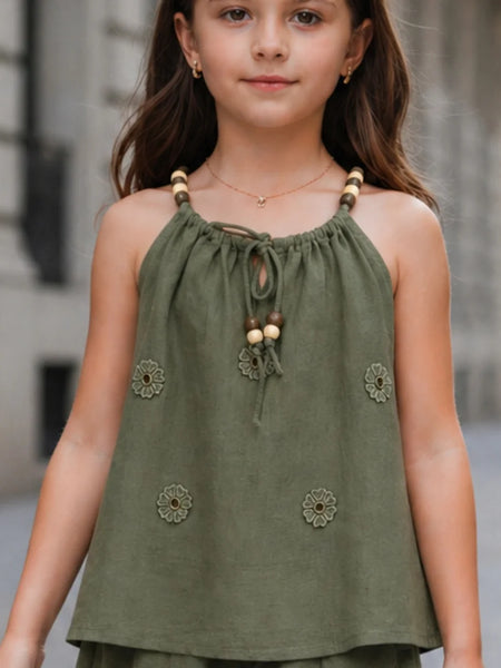 Young girl wearing a green top with floral embellishments in an urban setting