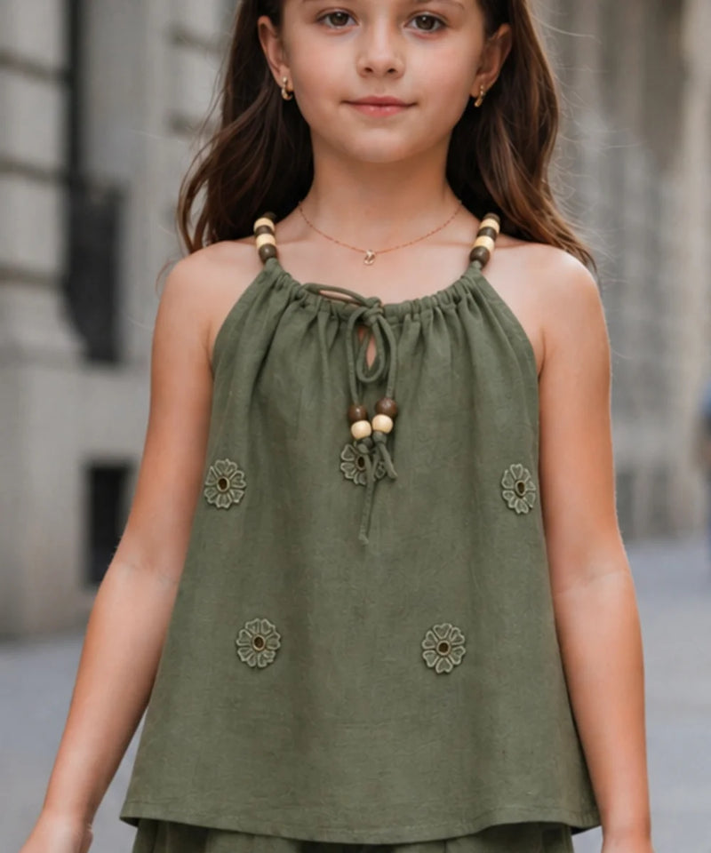Young girl wearing a green top with floral embellishments in an urban setting