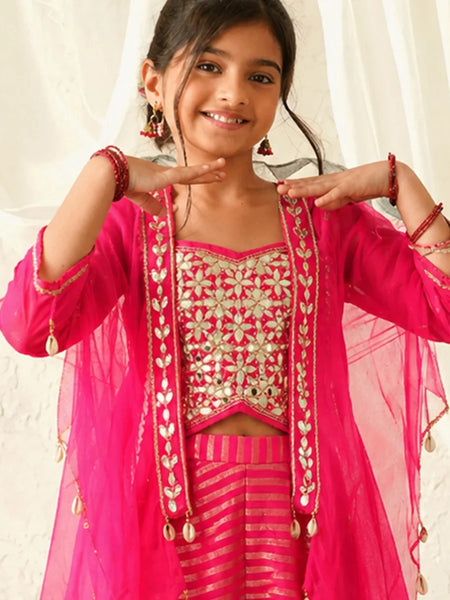 Young girl in a pink traditional outfit with gold embroidery against a white curtain background