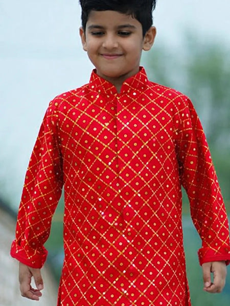 Child wearing a red traditional outfit with gold patterns outdoors.