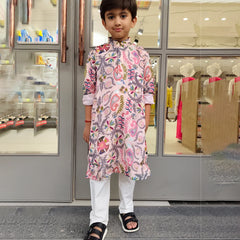 Child wearing a floral kurta with white pants standing in front of a store entrance.