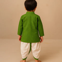 Child wearing a green traditional outfit with white dhoti on a beige background