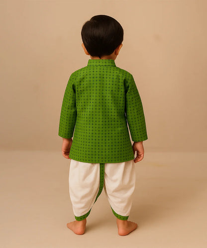 Child wearing a green traditional outfit with white dhoti on a beige background
