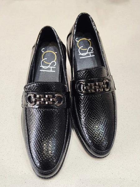 Black loafers with metallic accents on a beige background