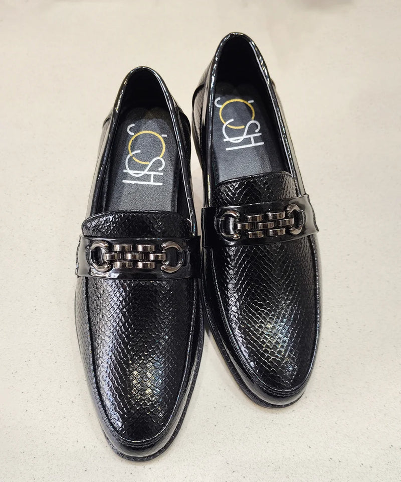 Black loafers with metallic accents on a beige background