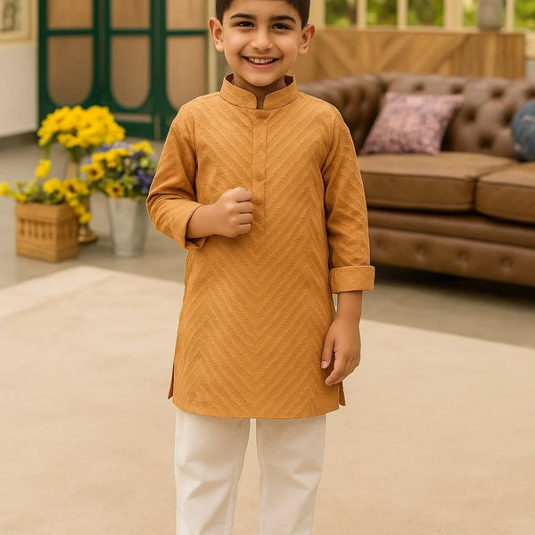 Young boy in a mustard kurta with white pants standing in a living room.