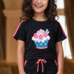 Child wearing a black t-shirt with a colorful cupcake design and black pants with pink accents.