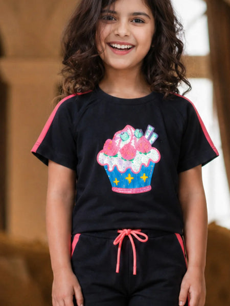 Child wearing a black t-shirt with a colorful cupcake design and black pants with pink accents.