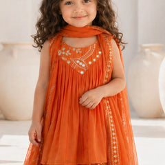 Young girl wearing an orange embroidered traditional outfit with a neutral background
