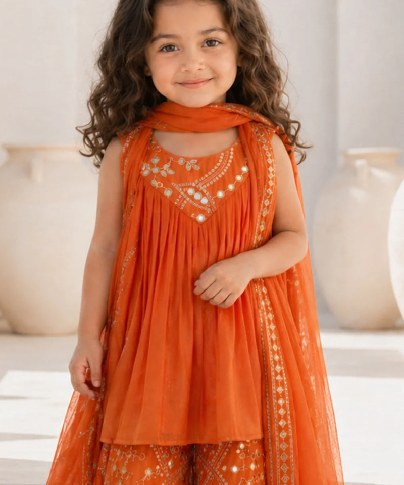 Young girl wearing an orange embroidered traditional outfit with a neutral background