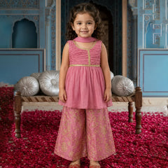 Young girl in a pink traditional outfit standing in a decorated room with red and silver decor.
