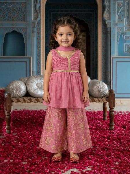Young girl in a pink traditional outfit standing in a decorated room with red and silver decor.
