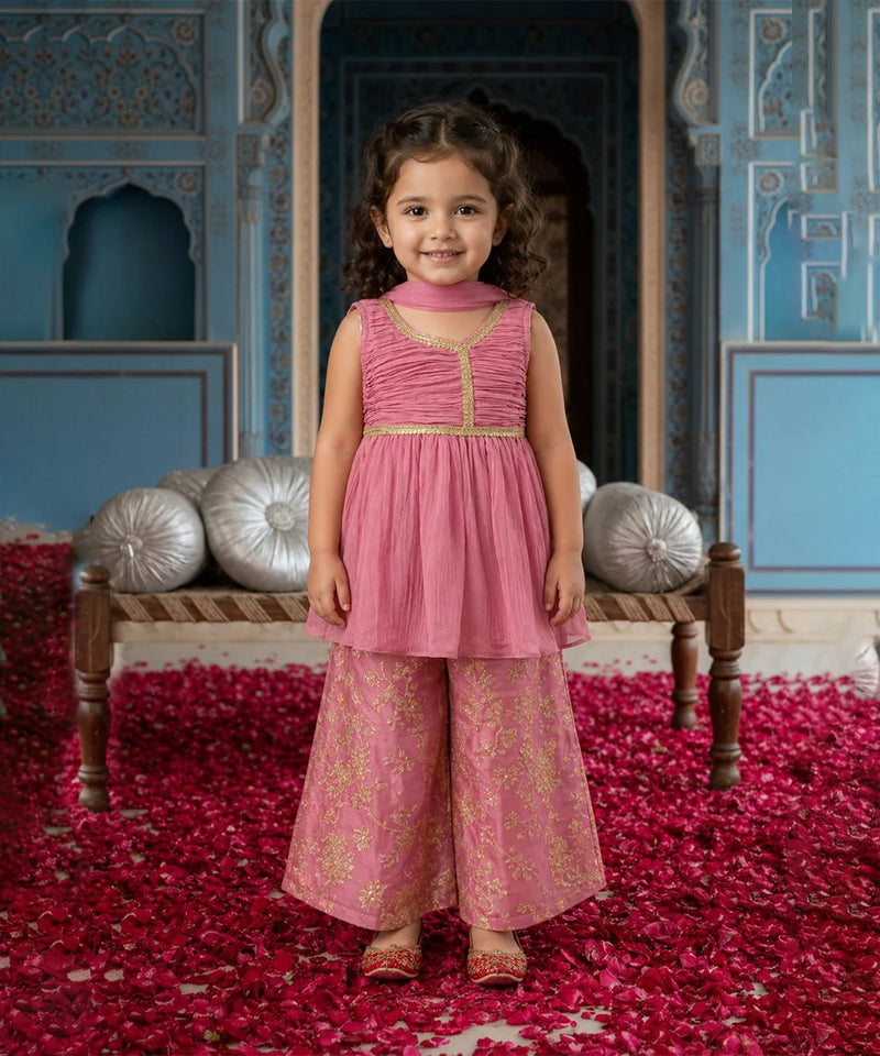 Young girl in a pink traditional outfit standing in a decorated room with red and silver decor.