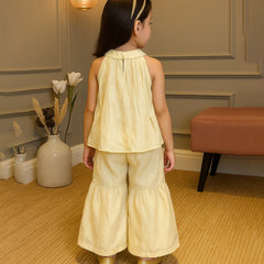 Young girl in a yellow outfit standing in a room with decorative elements.