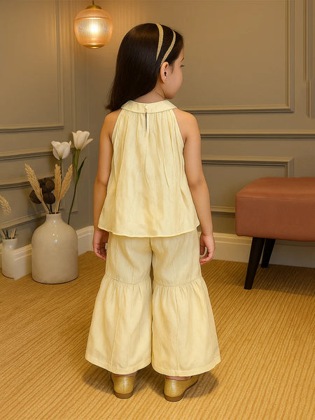 Young girl in a yellow outfit standing in a room with decorative elements.