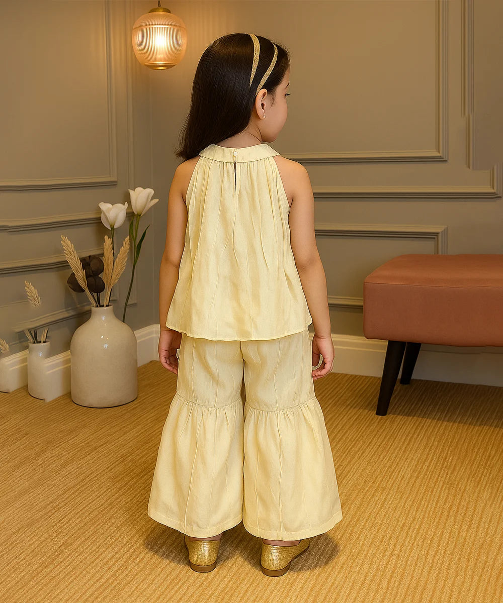 Young girl in a yellow outfit standing in a room with decorative elements.