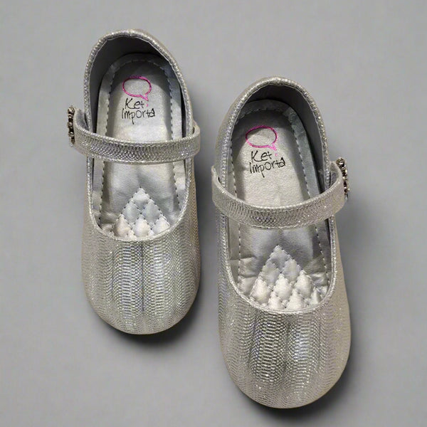 Close-up of shimmering silver party flats for girls with secure strap and jeweled flower, Jaipur

