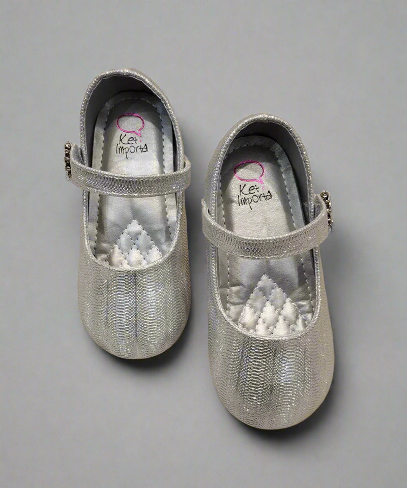 Close-up of shimmering silver party flats for girls with secure strap and jeweled flower, Jaipur

