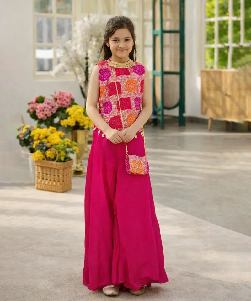 Young girl in a pink and orange traditional outfit standing indoors with flowers in the background.