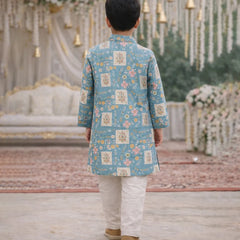 Child wearing a blue floral kurta with white pants in a decorated indoor setting.