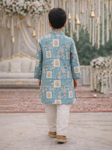Child wearing a blue floral kurta with white pants in a decorated indoor setting.