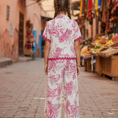 Woman in a floral dress walking down a street with market stalls.