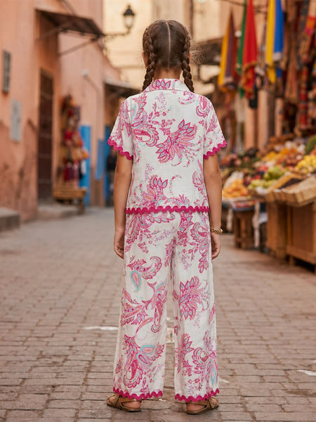 Woman in a floral dress walking down a street with market stalls.