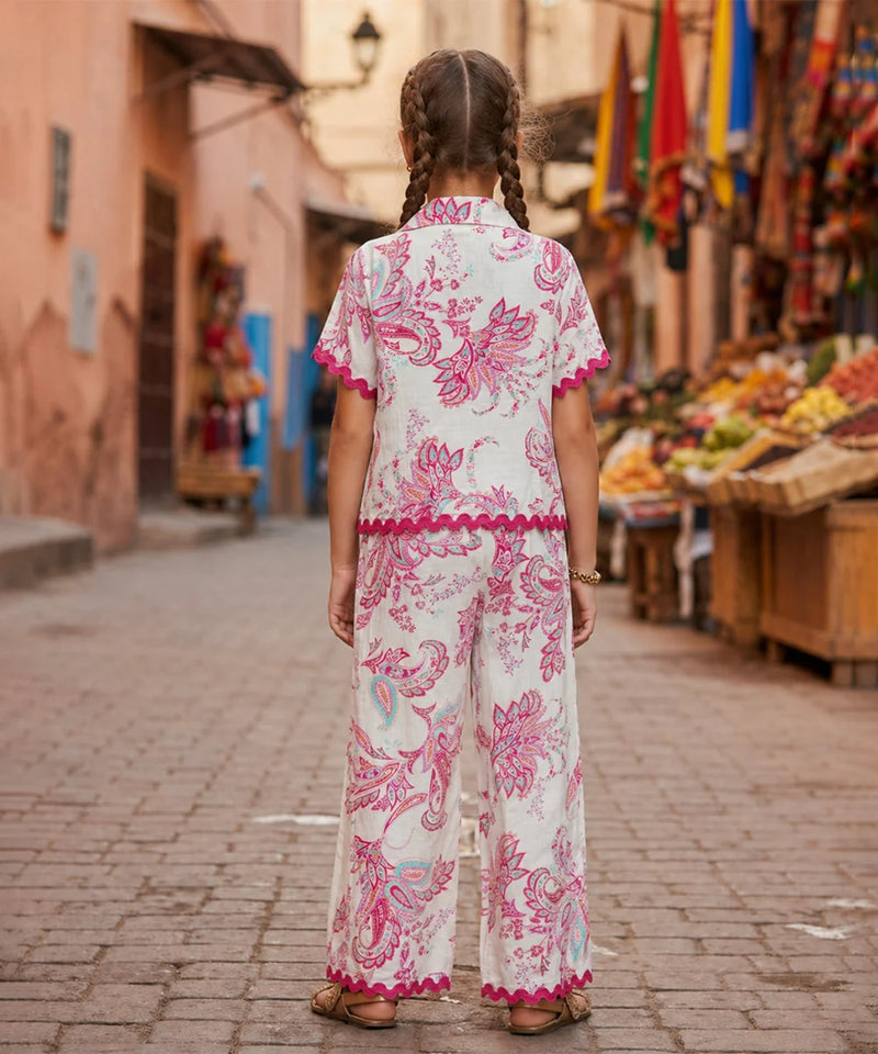 Woman in a floral dress walking down a street with market stalls.