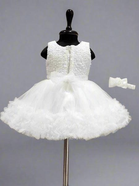 White flower girl dress on a mannequin with a wooden background