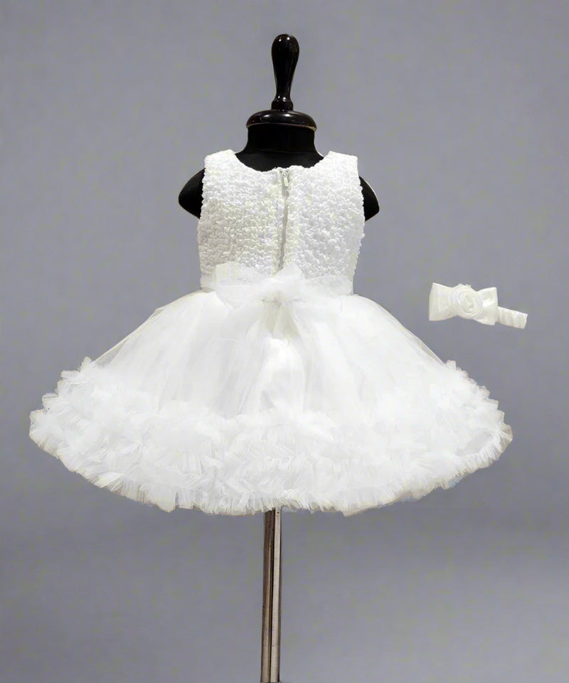 White flower girl dress on a mannequin with a wooden background