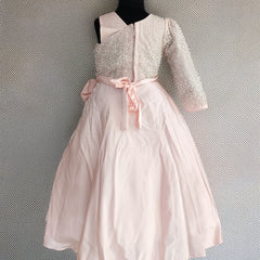 White dress with pink bow on a mannequin against a textured gray background