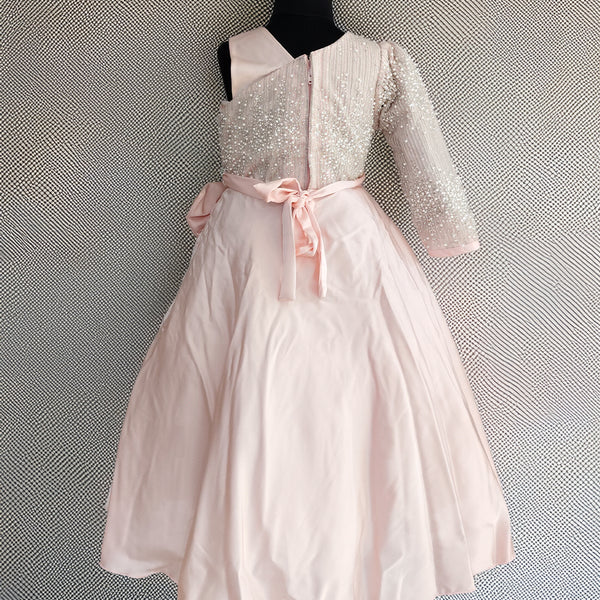 White dress with pink bow on a mannequin against a textured gray background