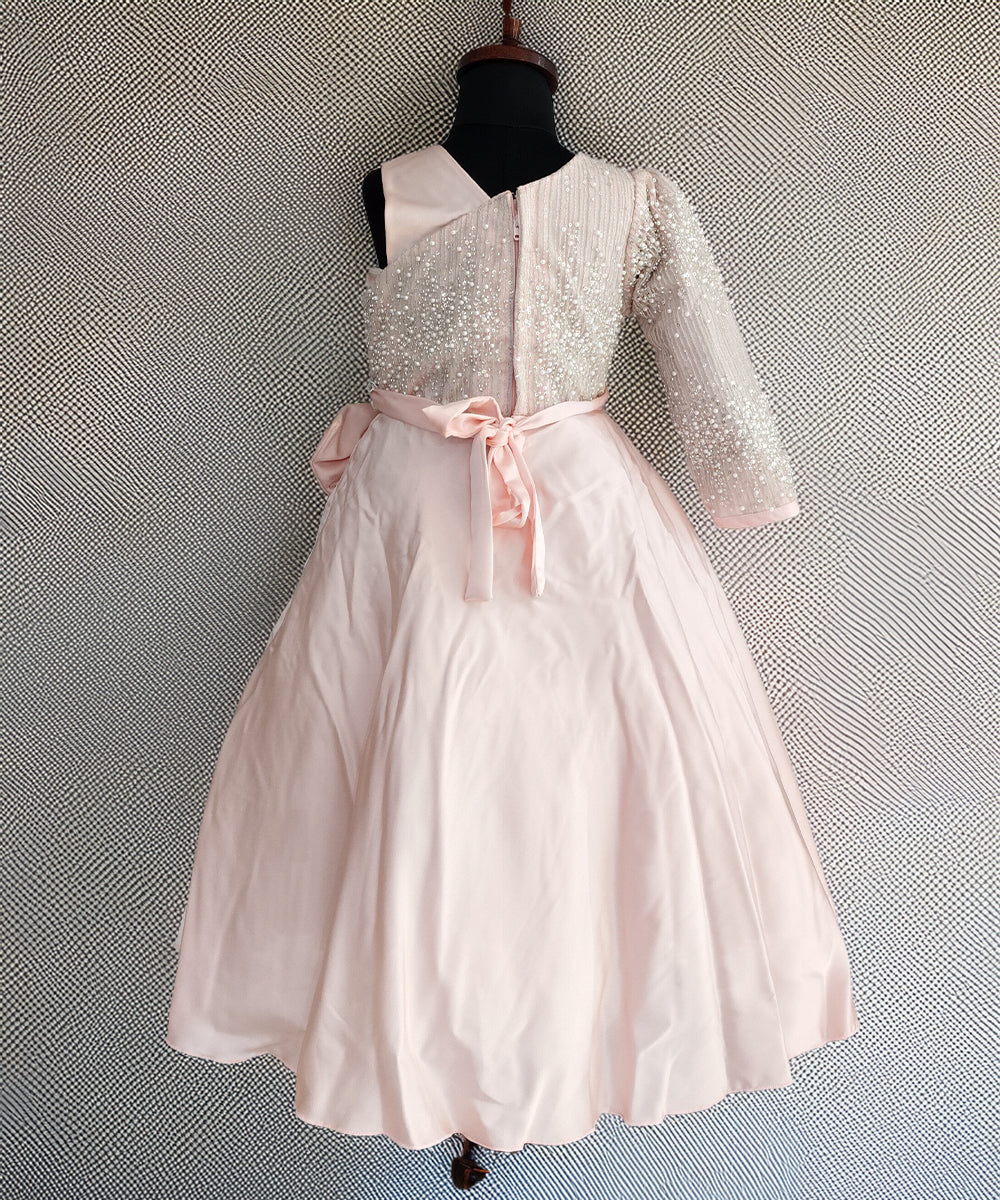White dress with pink bow on a mannequin against a textured gray background