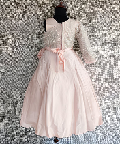 White dress with pink bow on a mannequin against a textured gray background