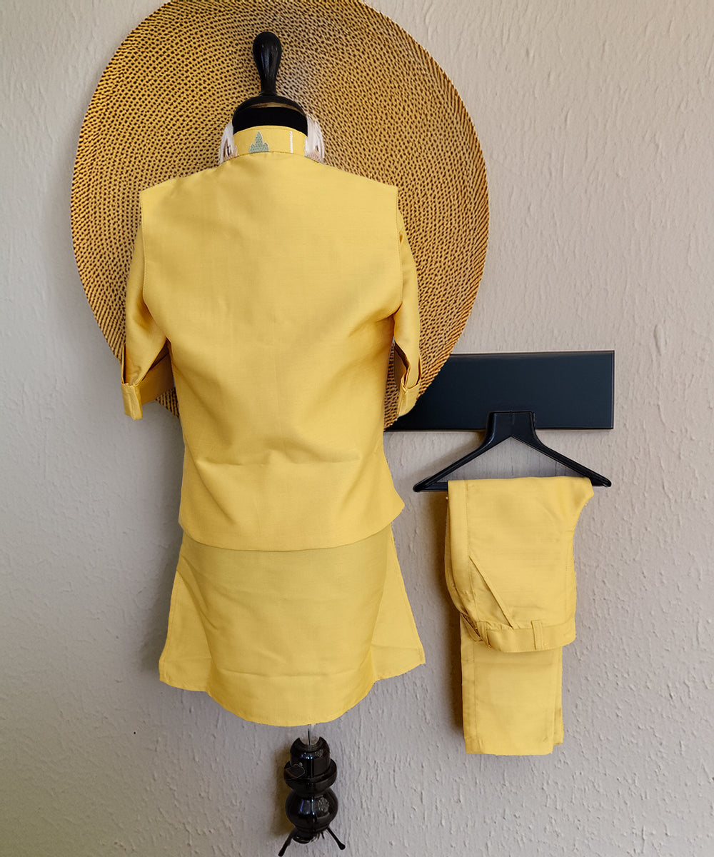 Yellow outfit on a mannequin and hanger against a plain wall