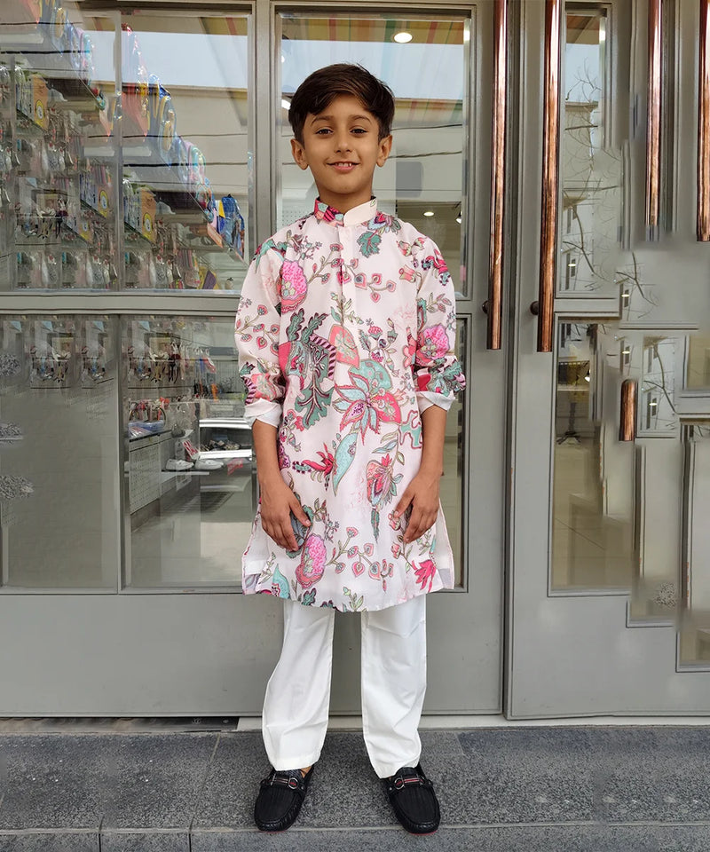 Young boy in a floral kurta standing outside a store.