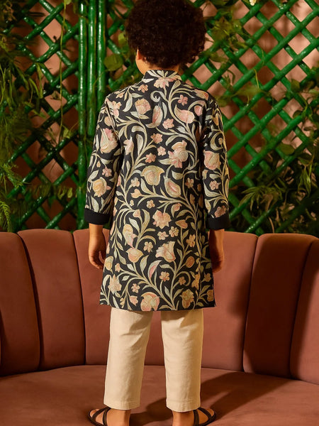 Person wearing a floral patterned outfit sitting on a pink couch with a green lattice background