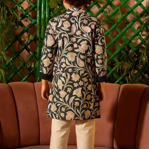 Person wearing a floral patterned outfit sitting on a pink couch with a green lattice background